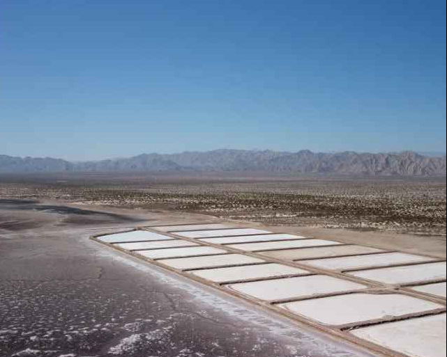 Salt evaporation ponds in a desert landscape with mountains in the background